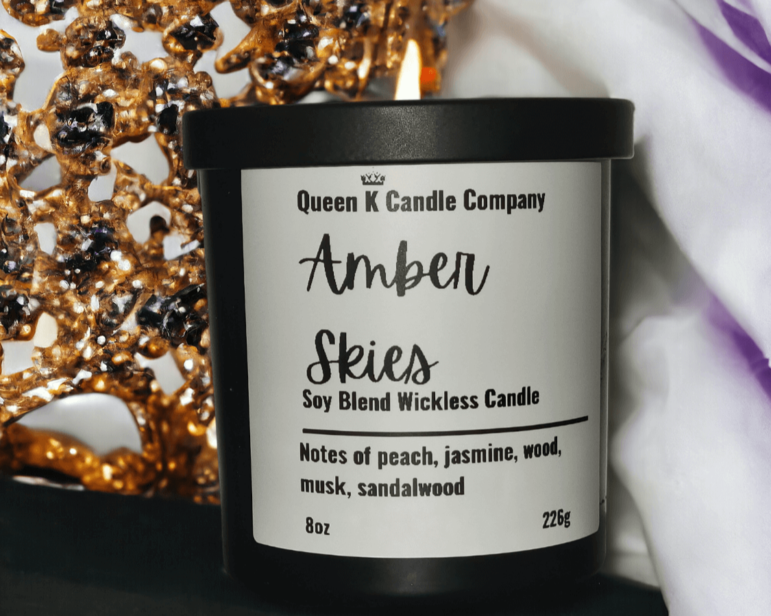 Candle with 'Queen K Candle Company' label in front of decorative candle holder