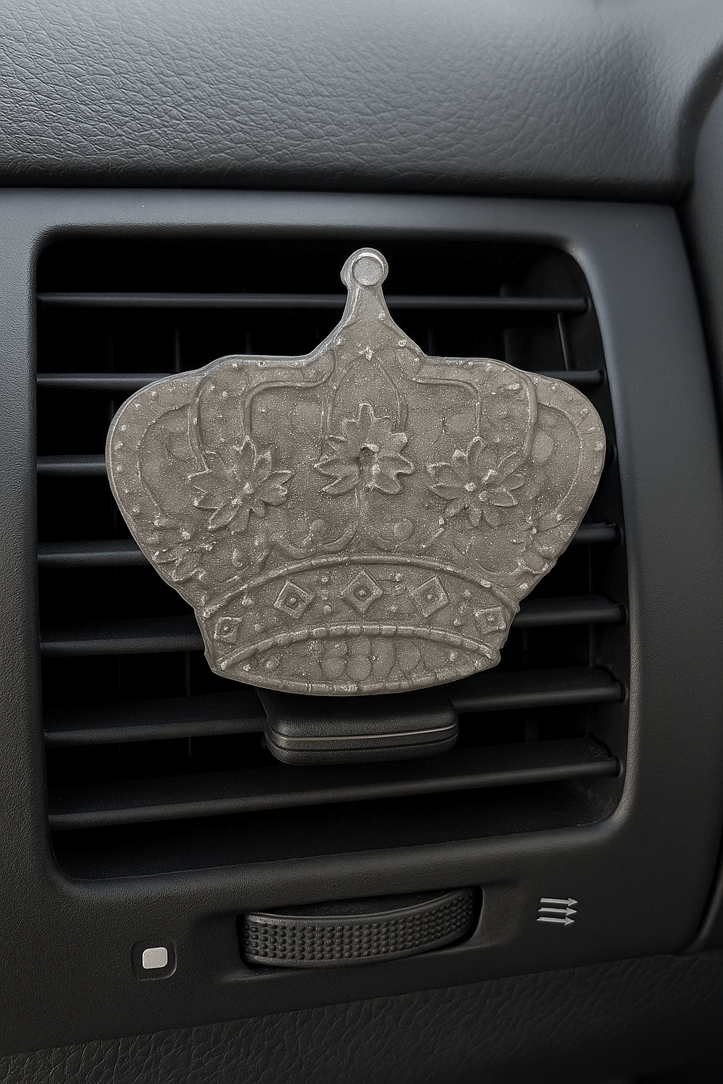 Decorative car air freshener shaped like a crown on a car vent.