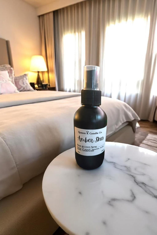 Bottle of amber spice room spray on a marble table in a bedroom setting