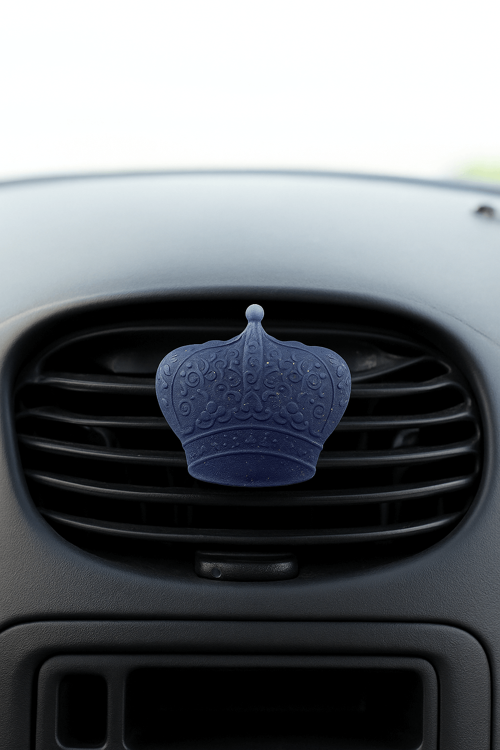 Blue car air freshener shaped like a crown on a car vent.