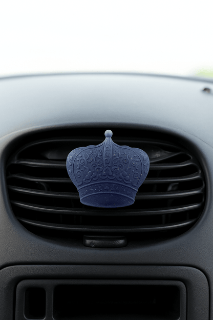 Blue car air freshener shaped like a crown on a car vent.