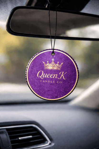 Car air freshener with 'Queen K Candle Co' branding hanging from a car's rearview mirror.