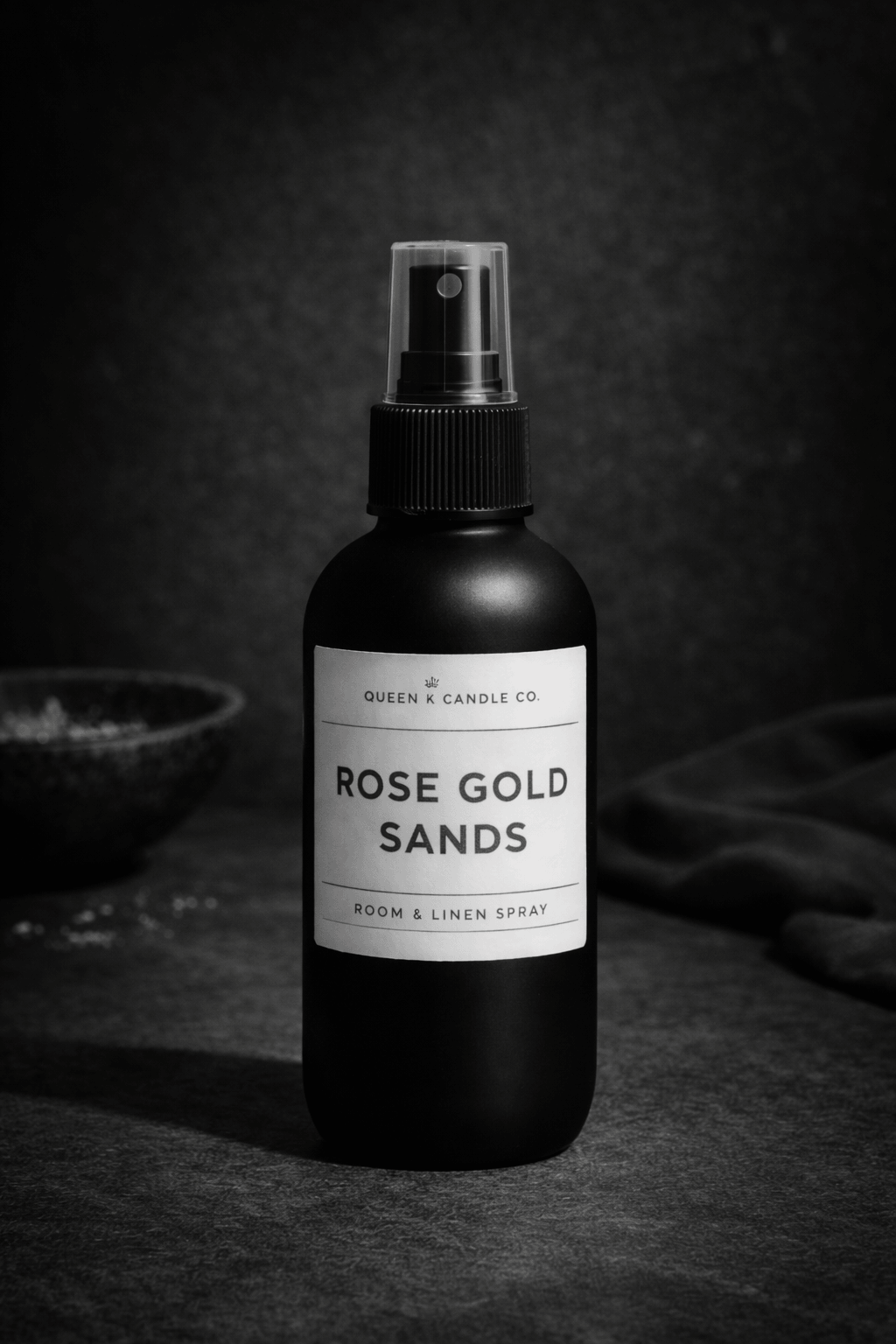 Black room & linen spray bottle labeled 'Rose Gold Sands' on a dark background