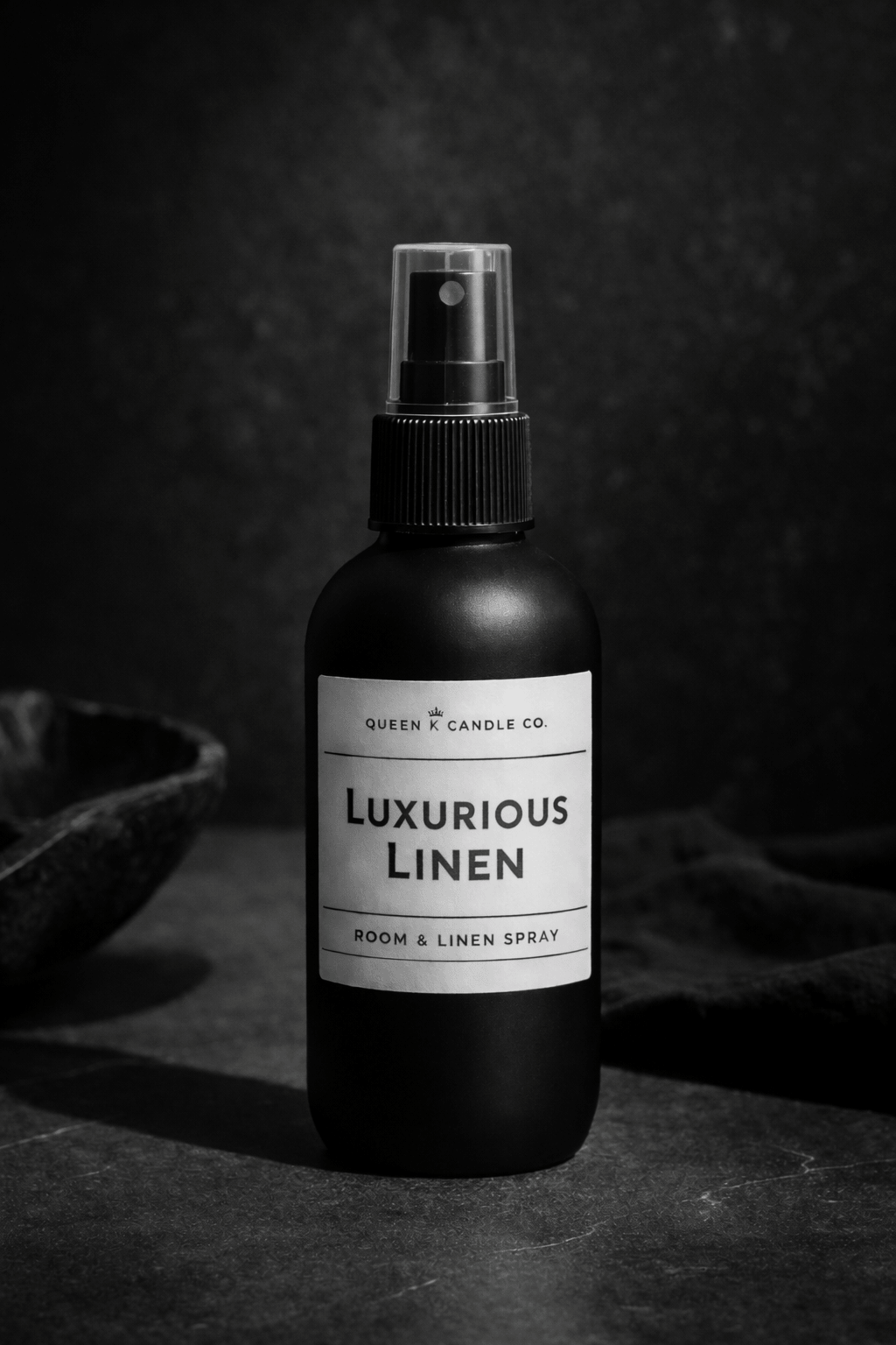 Black room & linen spray bottle labeled 'Luxurious Linen' on a dark background