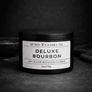 Black candle jar labeled 'Deluxe Bourbon' by Queen K Candle Co. on a dark background