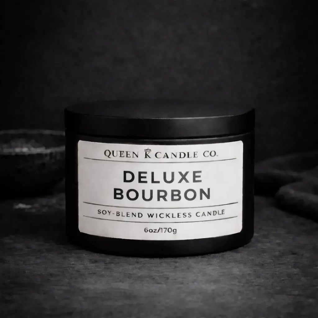 Black candle jar labeled 'Deluxe Bourbon' by Queen K Candle Co. on a dark background