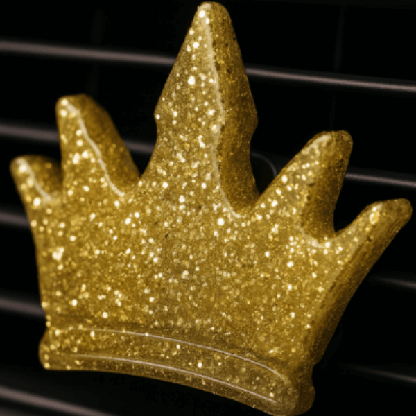 Gold glittery crown-shaped car air freshener on a car vent.